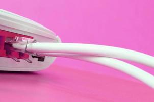 The Internet cable plugs are connected to the Internet router, which lies on a bright pink background. Items required for Internet photo