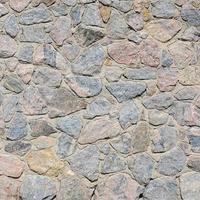 A gray stone wall, cemented between the rounded stones. Background texture photo