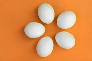 algunos huevos de pascua blancos sobre un fondo naranja brillante foto