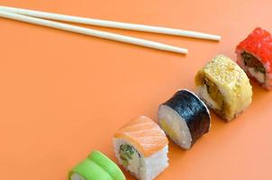 Different types of asian sushi rolls on orange background. Minimalism top view flat lay with Japanese food photo