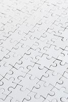 Close up of a white jigsaw puzzle in assembled state in perspective. Many components of a large whole mosaic are united photo