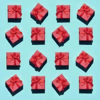 muchas pequeñas cajas de regalo de color rosa rojo sobre fondo de textura de papel de color azul pastel de moda en concepto mínimo. patrón abstracto foto