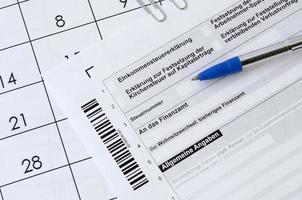 German tax form with pen lies on office calendar. Concept of tax paying in Germany photo