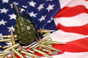 F1 frag grenade and many yellow bullets and cartridges on United States flag. Concept of gun trafficking on USA territory or spec ops photo