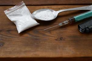 Syringe lighter and spoon full of white powder on wooden background. Heroin drug addiction concept photo