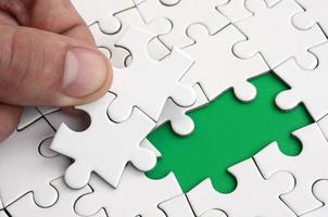 The human hand fills the last missing elements of the surface from the jigsaw puzzle. The concept of the completion of the initiated cases photo