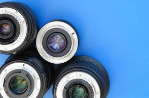 Several photographic lenses lie on a bright blue background. Space for text photo