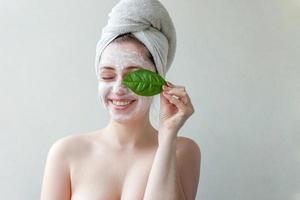 Woman face with green leaf and cream or nourishing mask photo