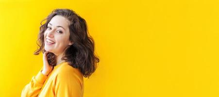 niña feliz sonriendo. retrato de belleza joven feliz mujer morena riendo positiva sobre fondo amarillo aislado. mujer europea. emoción humana positiva expresión facial lenguaje corporal foto