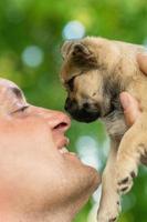 Happy young man touching nose of puppy photo