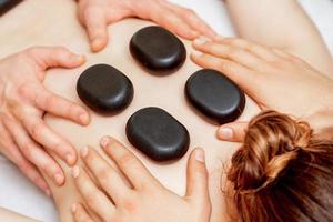 Male four hands laying stones on female back photo