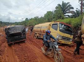 foto de carreteras de laterita dañadas que dan lugar a largas colas de vehículos muy cargados.