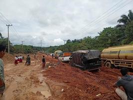 foto de carreteras de laterita dañadas que dan lugar a largas colas de vehículos muy cargados.