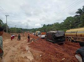 foto de carreteras de laterita dañadas que dan lugar a largas colas de vehículos muy cargados.