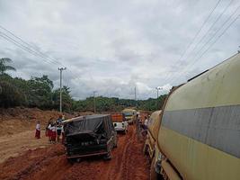 foto de carreteras de laterita dañadas que dan lugar a largas colas de vehículos muy cargados.