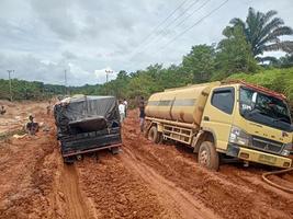 foto de carreteras de laterita dañadas que dan lugar a largas colas de vehículos muy cargados.