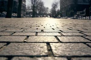 fondo de baldosas de pavimentación. primer plano de losas de pavimento en el fondo de calles, árboles y cielo en desenfoque. foto