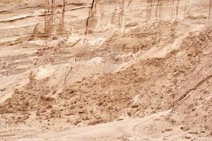 Crumbling sand wall in the cracks in the sand quarry. Closeup texture of sand in sand quarry photo