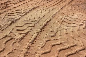 Tyre tracks on sand in brown tone. Abstract background and pattern. photo