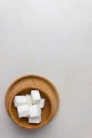 cubos de azúcar en platos de madera en la mesa de la cocina. vista superior, foto vertical. con espacio de copia