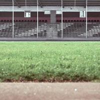 gradas vacías en el estadio. en primer plano hay un campo verde borroso. foto