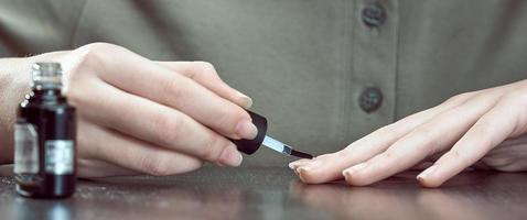 The girl paints her nails with a colorless varnish. photo