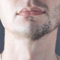 A man's half-shaved chin. White young man shaving. photo