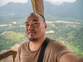 foto de retrato de turista gordo con hermosa vista en el pico de pha ngeun en la ciudad de vangvieng laos. ciudad de vangvieng la famosa ciudad de destino de vacaciones en lao.