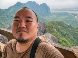 foto de retrato de turista gordo con hermosa vista en el pico de pha ngeun en la ciudad de vangvieng laos. ciudad de vangvieng la famosa ciudad de destino de vacaciones en lao.