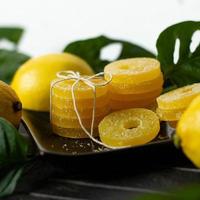 Lemon, orange and grapefruit slices in sugar isolated on a wooden background, close-up. Marmalade sweets. Sweets with citrus flavor. Candies photo