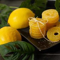 Lemon, orange and grapefruit slices in sugar isolated on a wooden background, close-up. Marmalade sweets. Sweets with citrus flavor. Candies photo