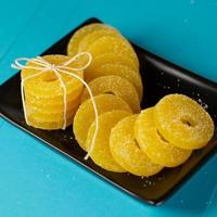 Lemon, orange and grapefruit slices in sugar isolated on a wooden background, close-up. Marmalade sweets. Sweets with citrus flavor. Candies photo