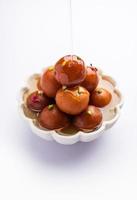 Gulab jamun or gulabjamun is an Indian sweet, served in a bowl as pile. closeup view photo