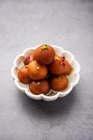 Gulab jamun or gulabjamun is an Indian sweet, served in a bowl as pile. closeup view photo