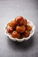 Gulab jamun or gulabjamun is an Indian sweet, served in a bowl as pile. closeup view photo