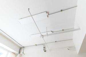 Electrical wires and pipes on house concrete ceiling background, plastic hoses with cables in empty room. Lines of pvc tubes, conduit after professional work. Renovation of home or factory interior photo