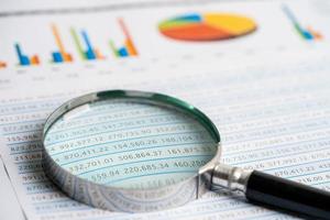 Magnifying glass on chart graph spreadsheet paper. Financial development, Banking Account, Statistics, economy, Stock exchange trading, Business office company meeting concept. photo