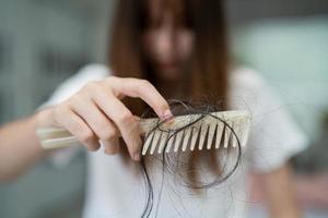 Asian woman have problem with long hair loss attach to comb brush. photo