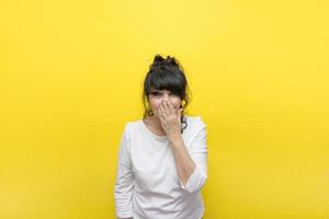 mujer de fondo amarillo se cubrió la boca con la mano de emociones desbordantes, el concepto no puede creer, ¿es realmente cierto? foto