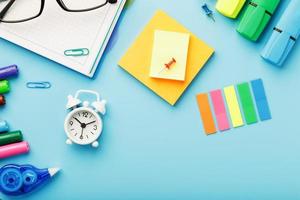 Colorful Stationery items with an alarm clock lie on a blue background. photo