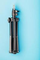 Folded Tripod on a blue background for a photo-video camera and flash on a blue background. photo