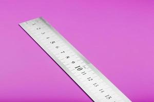 Metal ruler on a pink background close-up with a copy of the place for your text. photo