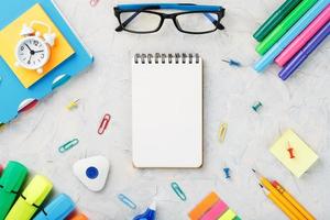 School stationery lies on a grey textured background with a Notepad in the center. photo