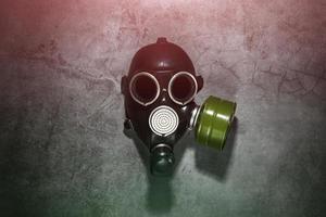 Gas mask on a black stone background with a green filter cartridge. Post-apocalyptic concept. photo