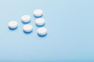 White medicinal tablets in the shape of a pyramid on a blue background. photo