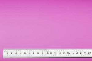 A metal ruler with a scale on a pink background is a superscape with a copy of the space for your text. photo