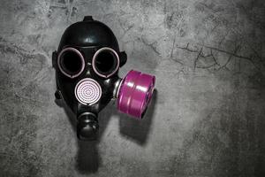 Gas mask on a black stone background with a pink filter cartridge. Post-apocalyptic concept. photo