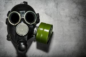 Gas mask on a black stone background with a green filter cartridge. Post-apocalyptic concept. photo