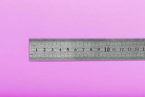 A metal ruler with a scale on a pink background is a superscape with a copy of the space for your text. photo