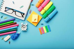 Colorful Stationery items with an alarm clock lie on a blue background. photo